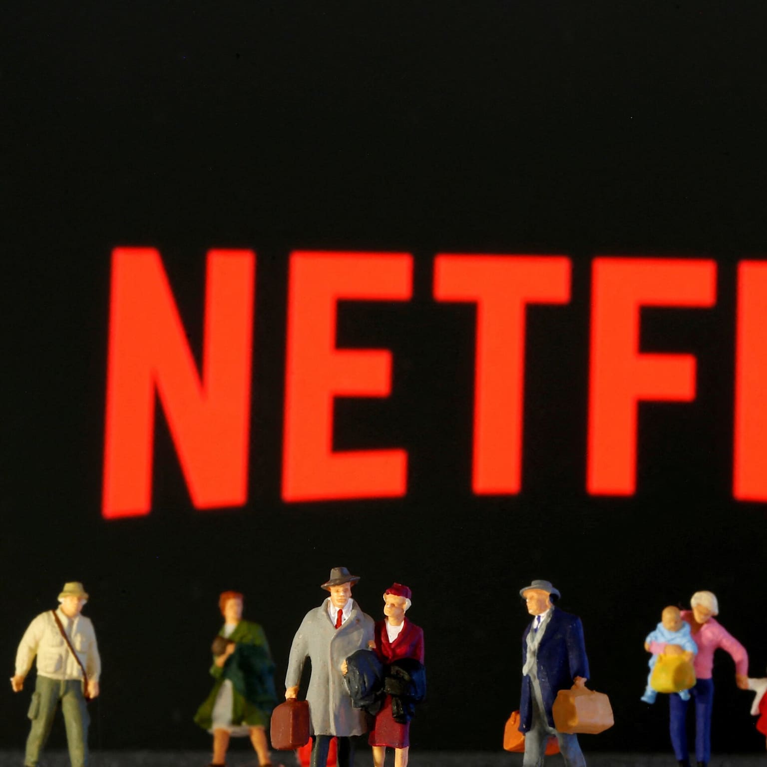 Miniature figures stand before a bright red Netflix logo, symbolizing the platform's presence