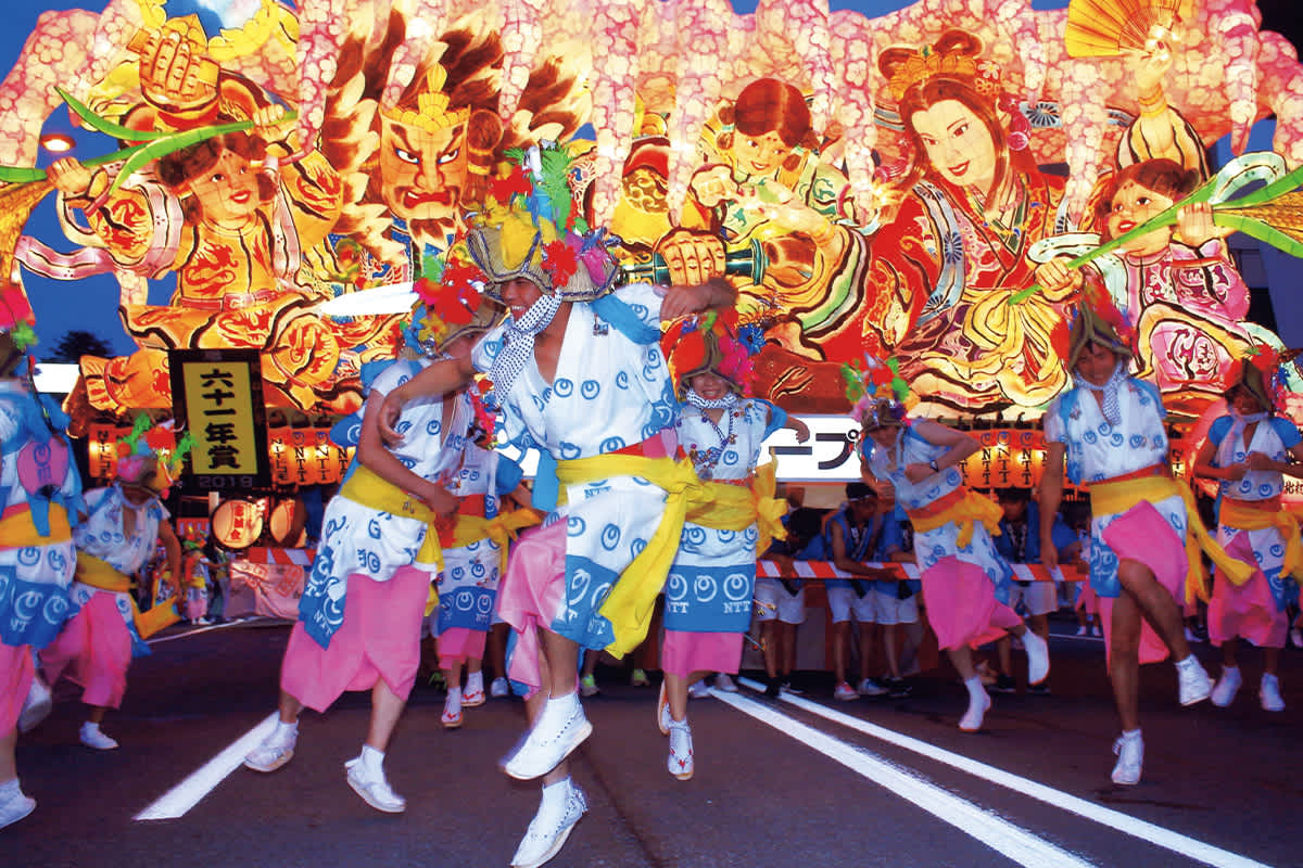 Energetic haneto dancers parade alongside illuminated nebuta floats during the vibrant Aomori Nebuta Festival
