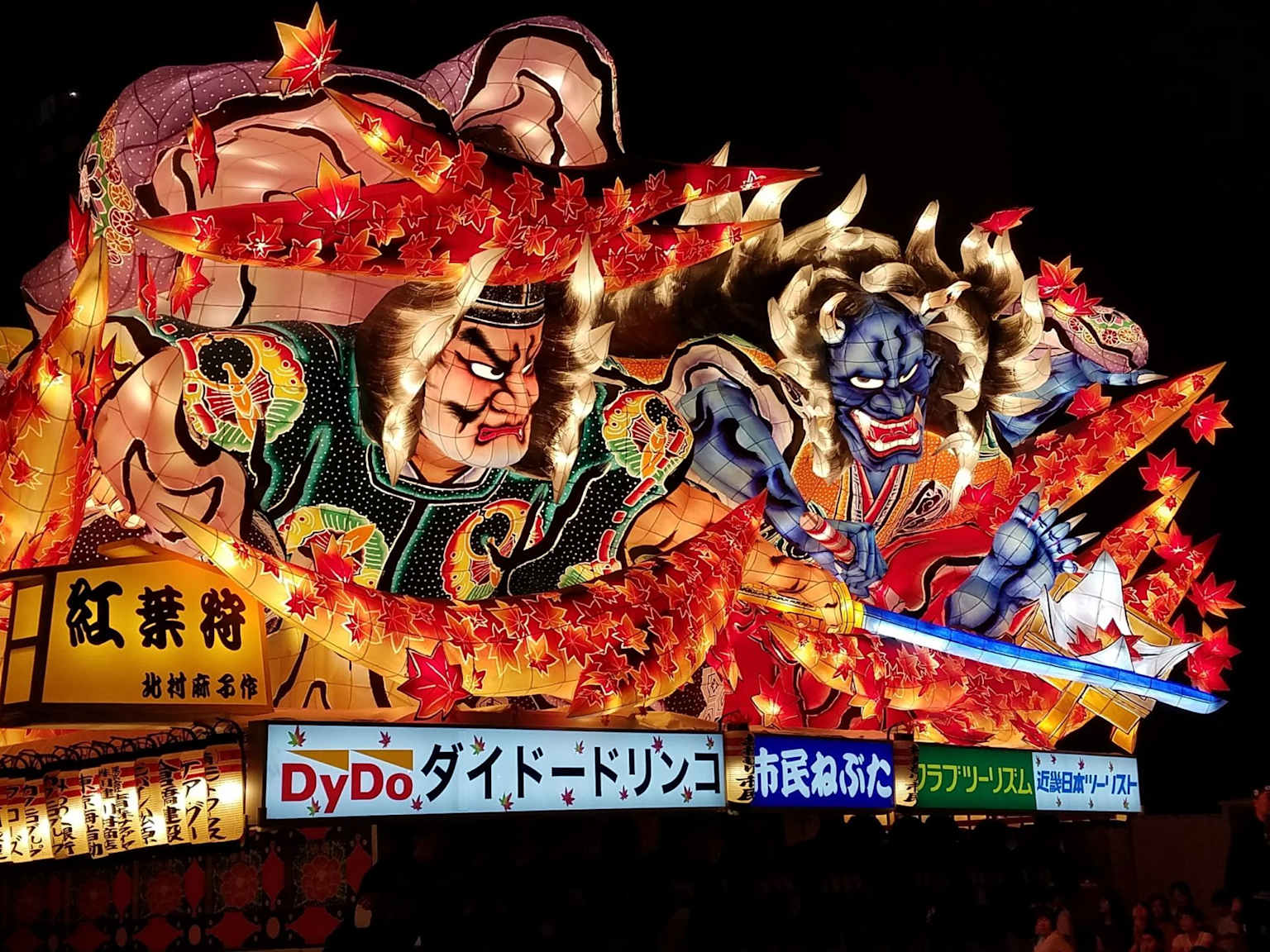 An illuminated nebuta float depicting two powerful figures during the Aomori Nebuta Festival